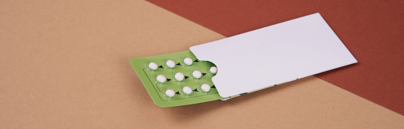 A package of birth control pills on a brown background.